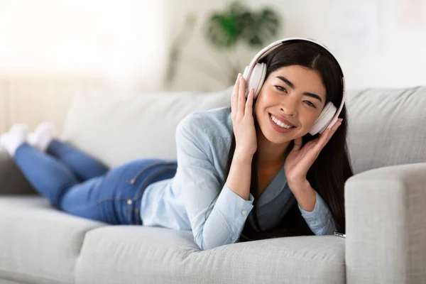 Wochenend-Pastime. Positive Asiatin trägt drahtlose Kopfhörer und hört zu Hause Musik — Stockfoto