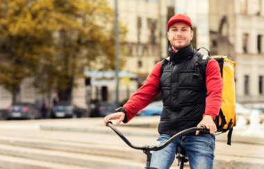 Bisikletli Kurye çantayla şehre yiyecek getiriyor.