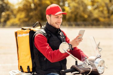 Smartphone uygulaması kullanan profesyonel kurye Scooter 'da yemek dağıtıyor.