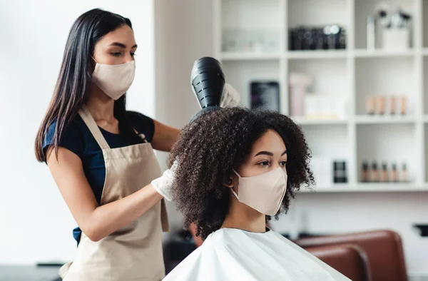 Peluquería y cliente con máscaras protectoras en el salón de belleza —  Fotos de Stock