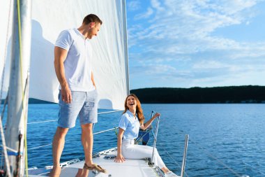 Yat güvertesinde dinlenen çift Yazı denizde yelken açarak geçiriyor