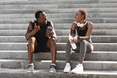 Sportif Afro-Amerikan çifti eğitimden sonra merdivenlerde dinleniyor.