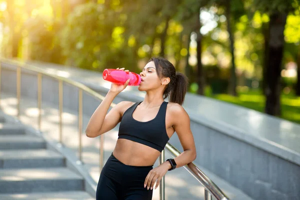 Atlética chica negra bebiendo agua mientras hace ejercicio en el parque — Foto de Stock