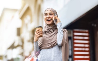Neşeli Arap kız telefonda kız arkadaşlarıyla konuşuyor.