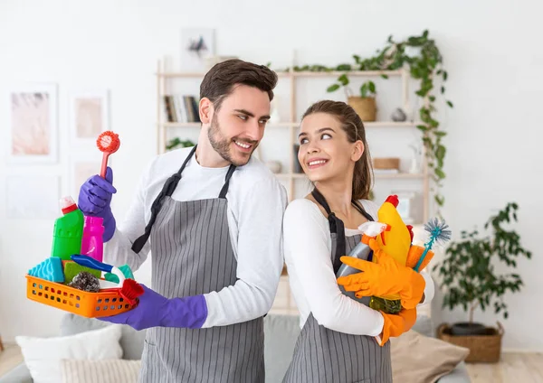Schoonmaakmiddelen voor reiniging. Glimlachende man en vrouw kijken elkaar aan en houden flessen met lege ruimte vast — Stockfoto