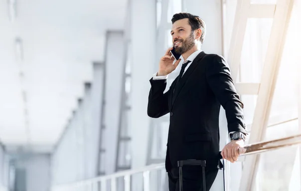 Mutlu iş adamı havaalanında duruyor, telefonla konuşuyor. — Stok fotoğraf