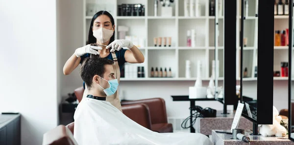 Fryzjer i klient mężczyzna w maskach ochronnych w salonie — Zdjęcie stockowe