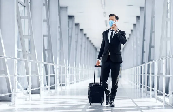 Wealthy entrepreneur talking on phone while walking by airport — Stock Photo, Image