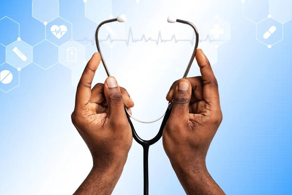 Médico afro-americano segurando estetoscópio em fundo azul, colagem com símbolos médicos na tela imaginária — Fotografia de Stock