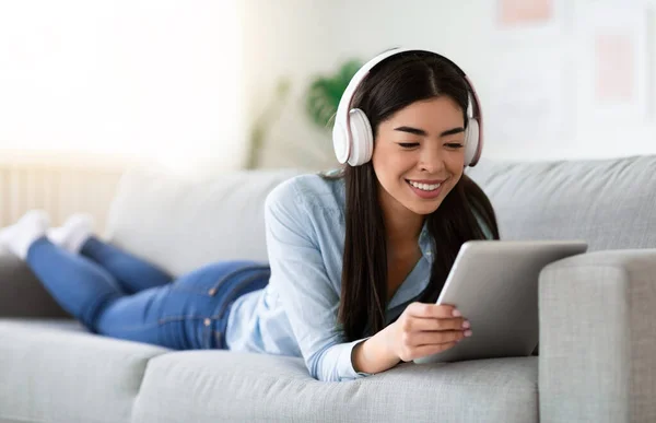 Tiempo libre. Sonriente chica coreana usando tableta digital y auriculares en casa —  Fotos de Stock