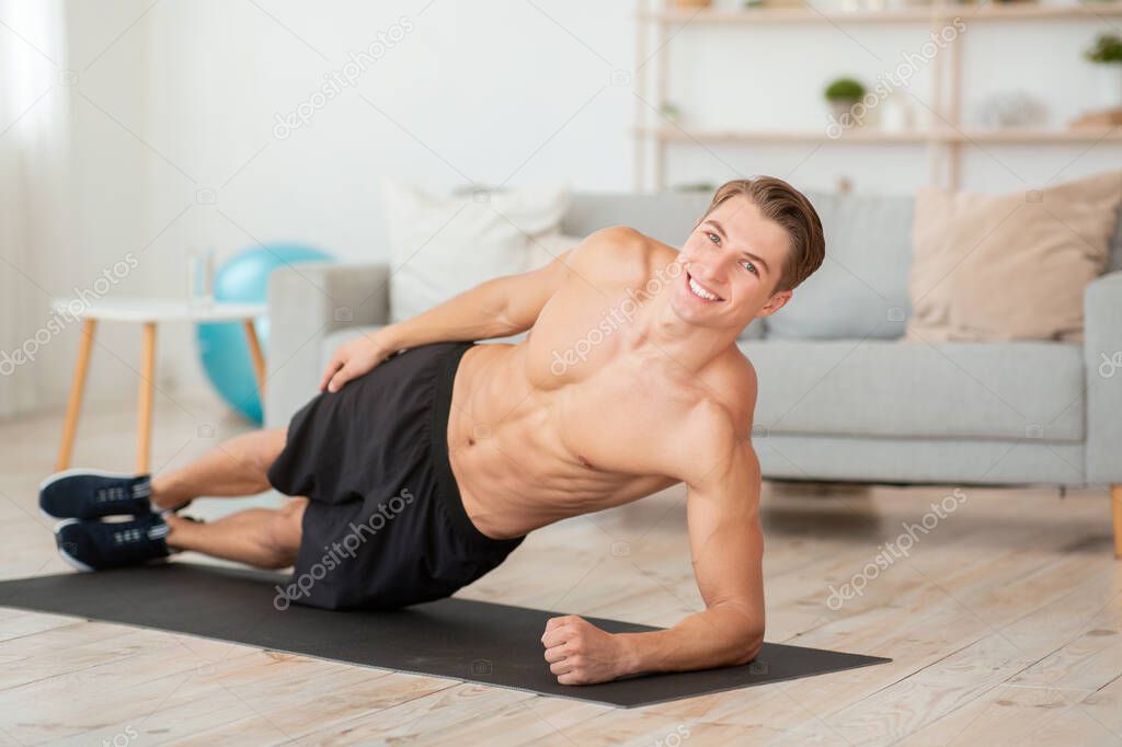 Muscular body and training result. Young man doing plank exercise on floor