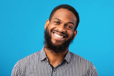 Mavi arka planda gülümseyen afro adam portresi