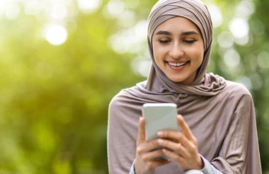 Modern akıllı telefon kullanan, park geçmişi olan güzel bir Arap kızı.