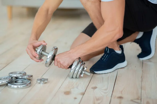 Entraînement de force à la maison. L'homme met des disques sur des haltères pour l'entraînement — Photo