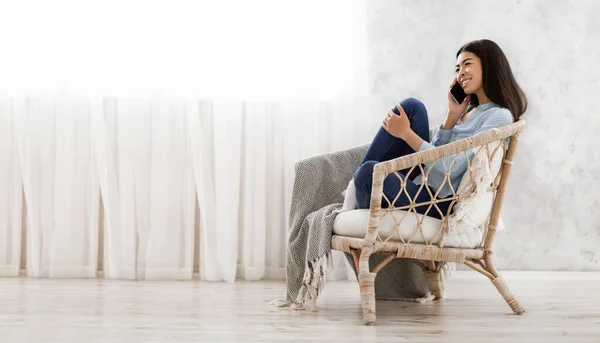 Menina coreana feliz falando no celular em casa enquanto relaxa na cadeira — Fotografia de Stock