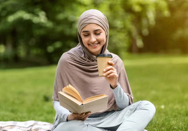 Chica árabe leyendo libro y tomando café en el parque de la ciudad — Foto de Stock