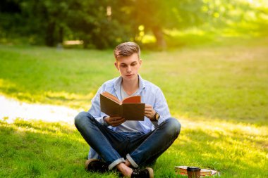 Açık hava eğlencesi. Genç yakışıklı çocuk parkta dinleniyor.