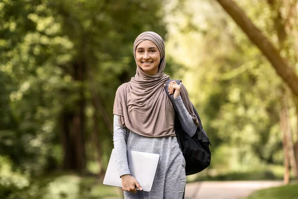 Mujer musulmana sonriente en hijab con portátil posando en el parque — Foto de Stock