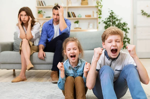 Pajkos gyerekek Helytelen viselkedés Sikoltozás Ül közel kimerült szülők otthon — Stock Fotó