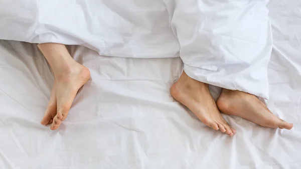 Probleme în relația de familie. Picioare de bărbat și femeie în pat alb la distanță — Fotografie, imagine de stoc