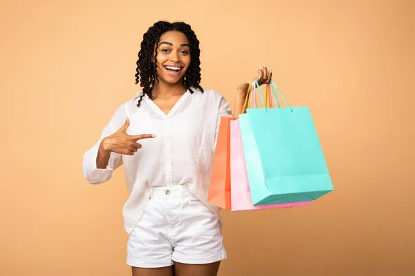 Felice cliente puntando dito a borse Shopper su sfondo beige — Foto Stock