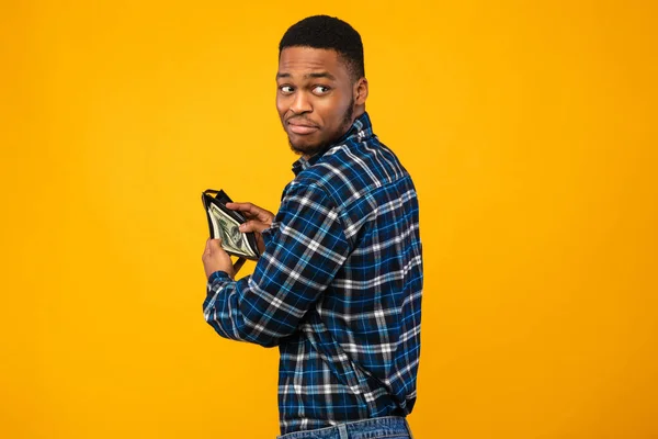 Sneaky Black Man segurando carteira com dinheiro no fundo amarelo — Fotografia de Stock