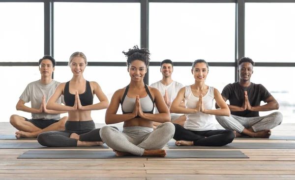 Wellness-konceptet. Glad mångkulturell ungdom som tränar yoga i modern ljusstudio — Stockfoto