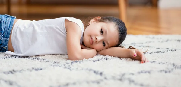 Aburrido Chino Niña acostada en el suelo en casa, Panorama —  Fotos de Stock