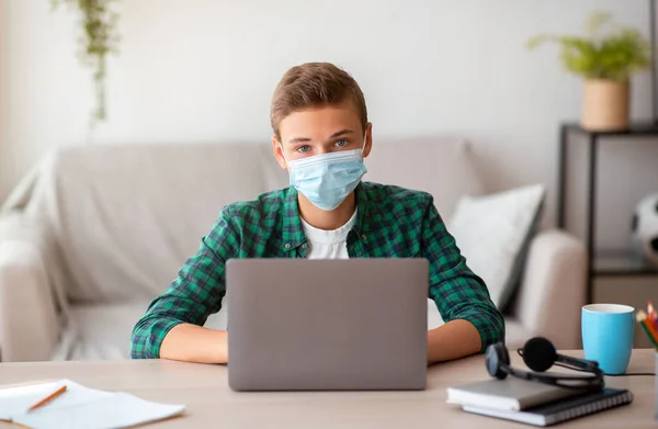 School boy in protective mask typing on laptop — Stock Photo, Image