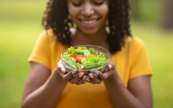 Egészséges evés. Boldog fekete lány kezében tál friss zöldség saláta szabadban, szelektív fókusz — Stock Fotó