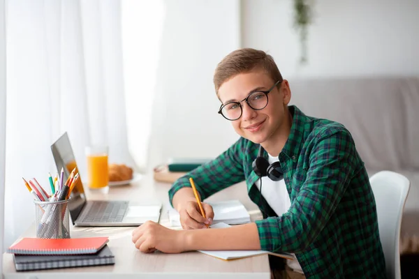 Szczęśliwy nastolatek robi pracę domową w domu — Zdjęcie stockowe