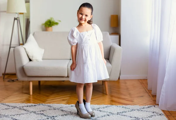 Adorable chica asiática usando mamás zapatos de tacón alto en interiores — Foto de Stock