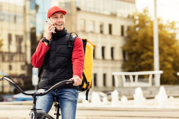Courier Guy conversando no telefone móvel sentado na bicicleta ao ar livre — Fotografia de Stock