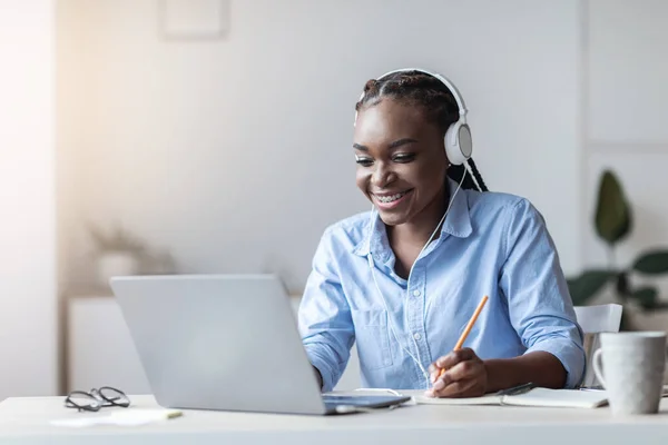 Black Female Office Employee Watching Webinar On Laptop And Taking Notes — Stock fotografie