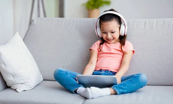 Menina coreana usando Tablet computador usando fones de ouvido sentados dentro de casa — Fotografia de Stock