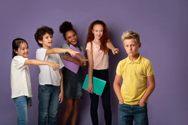 Pára com o bullying nas escolas. Crianças viciosas rindo de menino loiro triste sobre fundo lilás — Fotografia de Stock