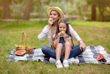 Mutlu Anne ve Kız Elma Yiyiyor Ekose üzerinde oturuyor Açık havada