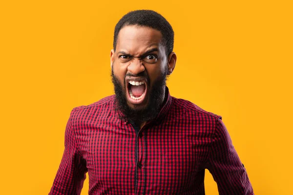 Enojado afro hombre gritando en amarillo estudio —  Fotos de Stock