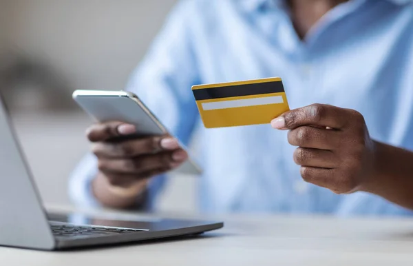 Betalning online. Oigenkännlig svart kvinna med smartphone och kreditkort på kontoret — Stockfoto