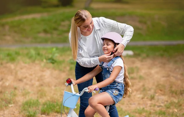 Liten flicka lär sig att cykla med mamma utomhus — Stockfoto