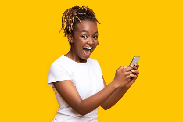 Mulher negra excitada usando telefone celular, tem novo aplicativo agradável — Fotografia de Stock