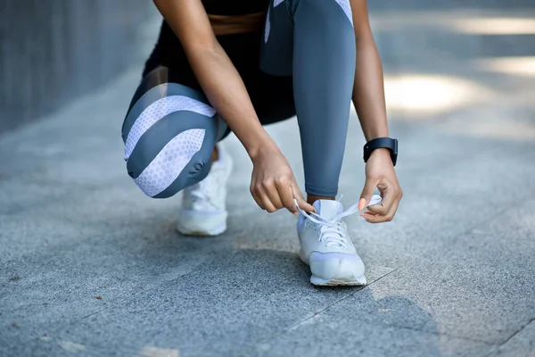 Primer plano de chica negra en ropa deportiva atando cordones de zapatos antes de correr — Foto de Stock