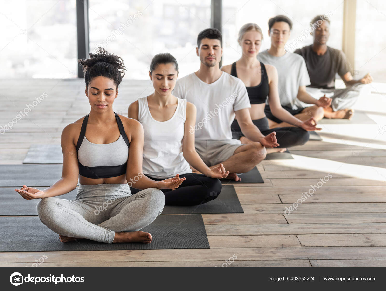 Aula de Meditação. Grupo de jovens aptos a praticar Yoga no estúdio de luz  fotos, imagens de © Milkos #403952224