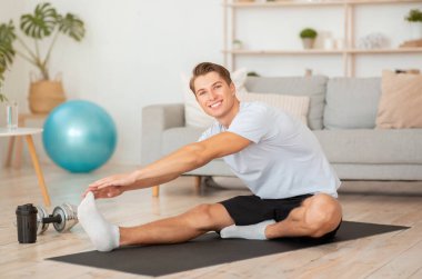 Egzersizden sonra evde geriniyorum. Mutlu adam koçu dersleri olan takipçiler için video çekiyor.