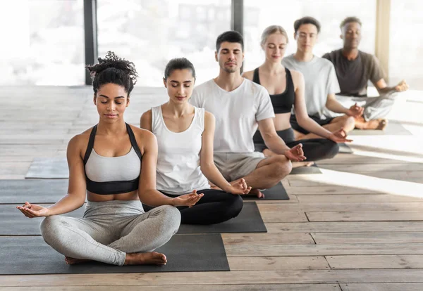 Meditationsklass. Grupp bestående av lämpliga ungdomar som tränar yoga i ljusstudio — Stockfoto