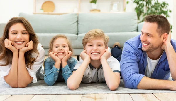 Família feliz de quatro deitado no chão posando em casa — Fotografia de Stock