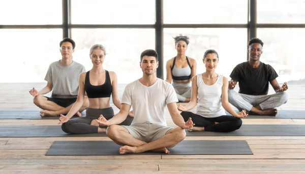 Prática de Yoga. Sorrindo Jovens Desportistas Meditando Juntos Com Treinador No Estúdio — Fotografia de Stock