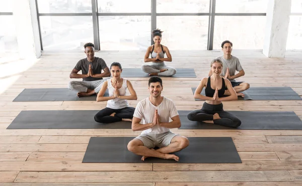 Diverses personnes sportives assistant à des cours de yoga en studio, assis en position lotus — Photo