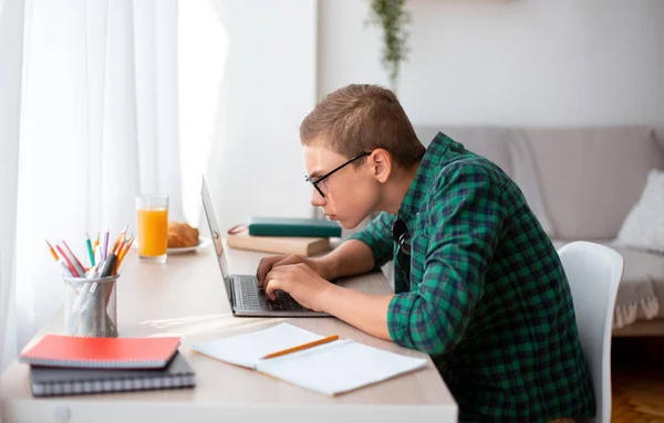 Konzentrierter Nerd-Junge mit Laptop, der zu Hause an einem Projekt arbeitet — Stockfoto