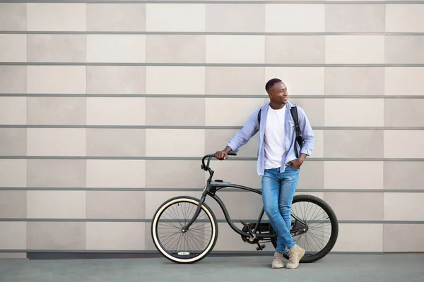 Homem afro-americano feliz com bicicleta perto da parede de tijolo na cidade, espaço para texto — Fotografia de Stock